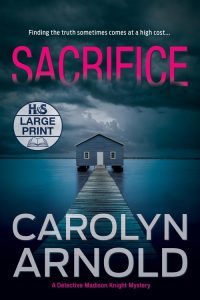 Sacrifice Large Print Edition by Carolyn Arnold, a boathouse at the end of a dock sitting in a frozen river under a cloudy sky