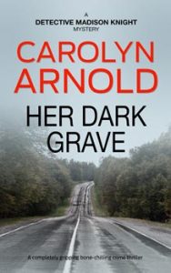 Her Dark Grave by Carolyn Arnold, woman with a red suitcase walking down the shoulder of a road with a stormy sky overhead.