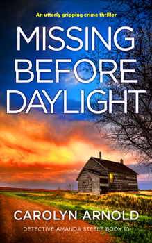 Missing Before Daylight by Carolyn Arnold, an old cabin with a light on in the window, overgrown grass on the side of a dirt road, under a fiery early morning sky.